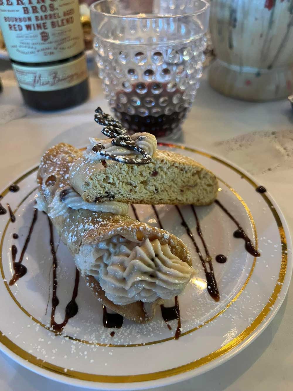 cannoli and biscotti on plate with wine in background