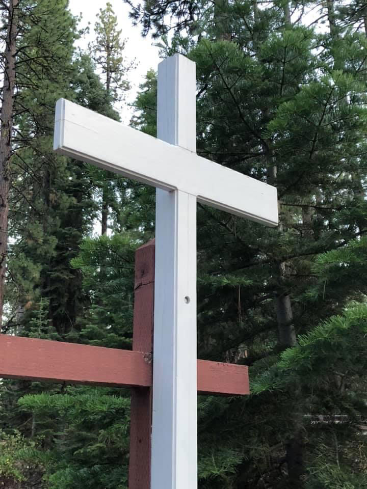 white cross in front of trees